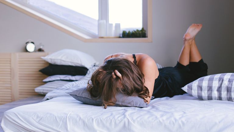 woman in bed stressed with her hands between her head, meant to symbolize anorgasmia in women 