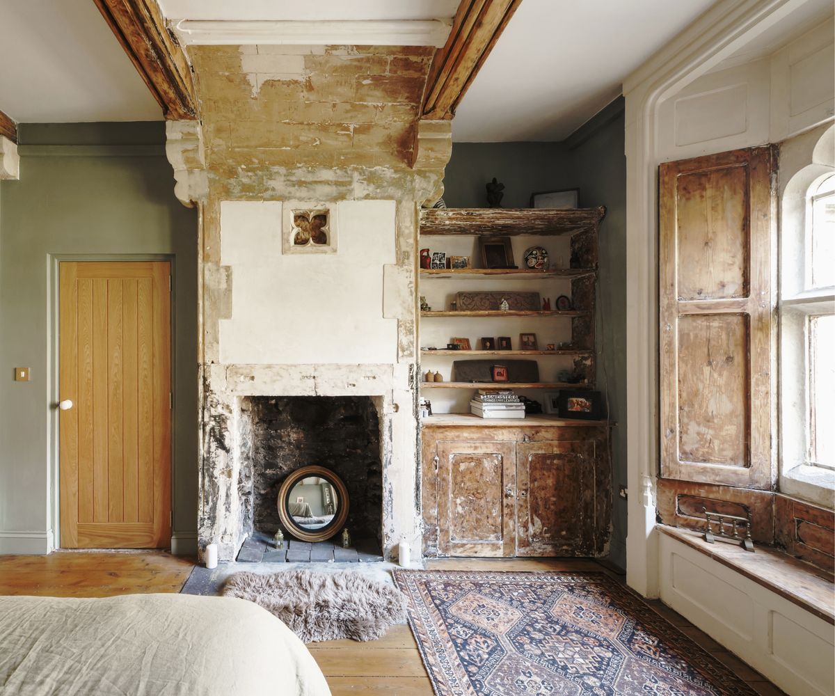 Room with wooden shutters on window, empty fireplace, and built in shelving unit