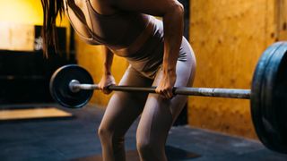 Woman holding barbell with weights in the gym