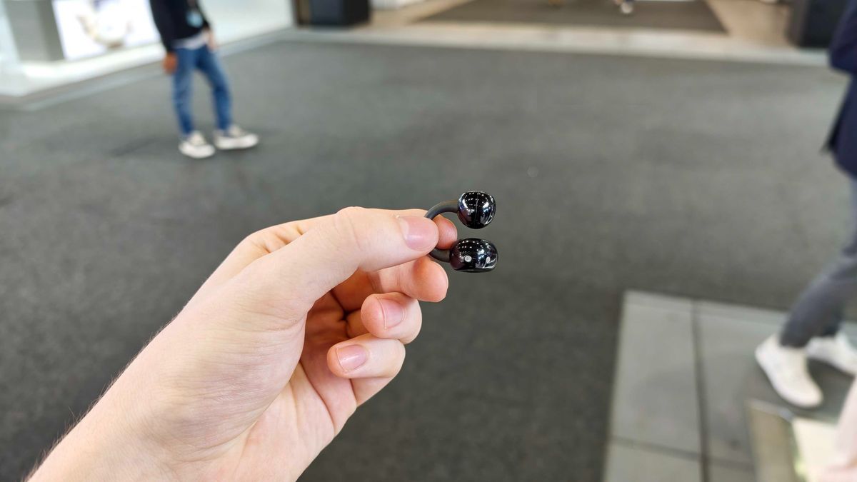 Noise Master Buds Open, held in a hand in a big expo center