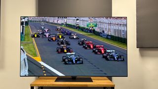 The 65-inch LG G5 OLED TV pictured on a wooden rack. On the screen is a still from Netflix F1 series Drive to Survive.