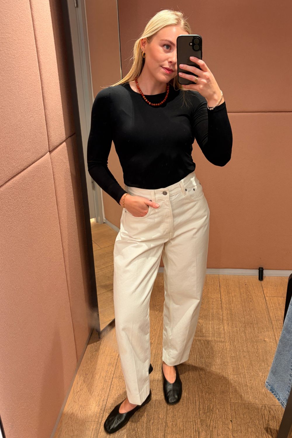 Shopping editor, Florrie, wears the COS Umbra tapered jeans, black long-sleeved top, black ballet flats and red bead necklace