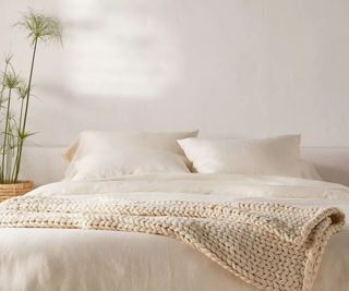 Neutral bedding with woven throw in cream and bamboo plant