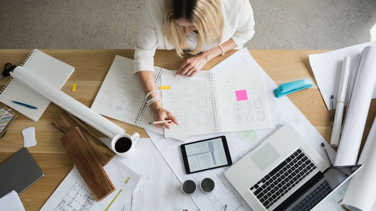 Woman Working with Paper &amp; Laptop on Desk