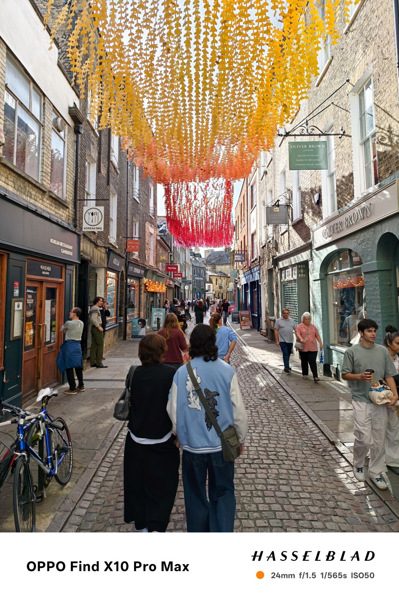 Busy pedestrian street beneath orange, pink and red hanging decorations.