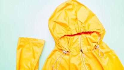 A yellow waterproof jacket laid out on a background showing how to wash a waterproof jacket
