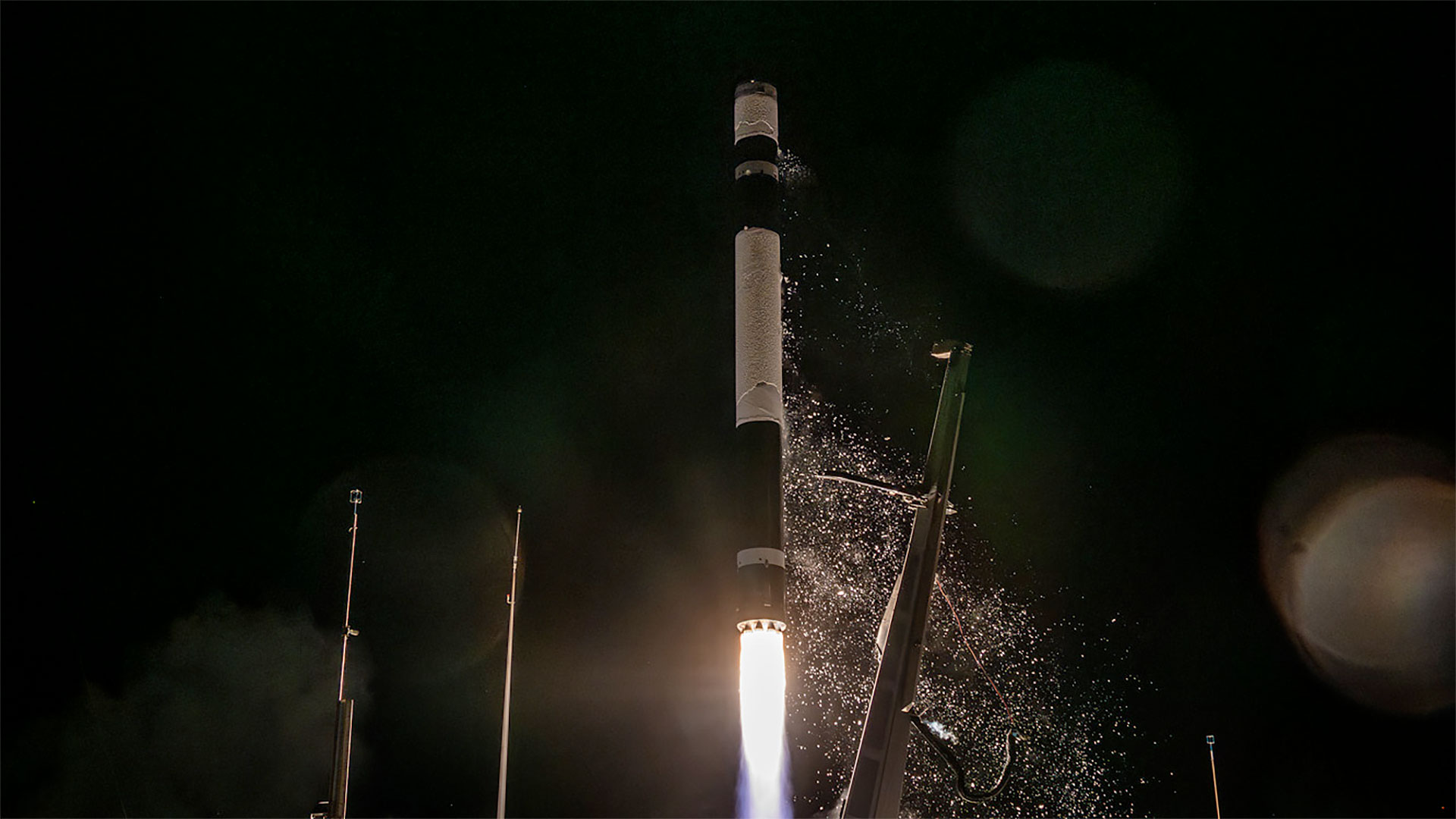 a white and black rocket lifts off into the black sky of night