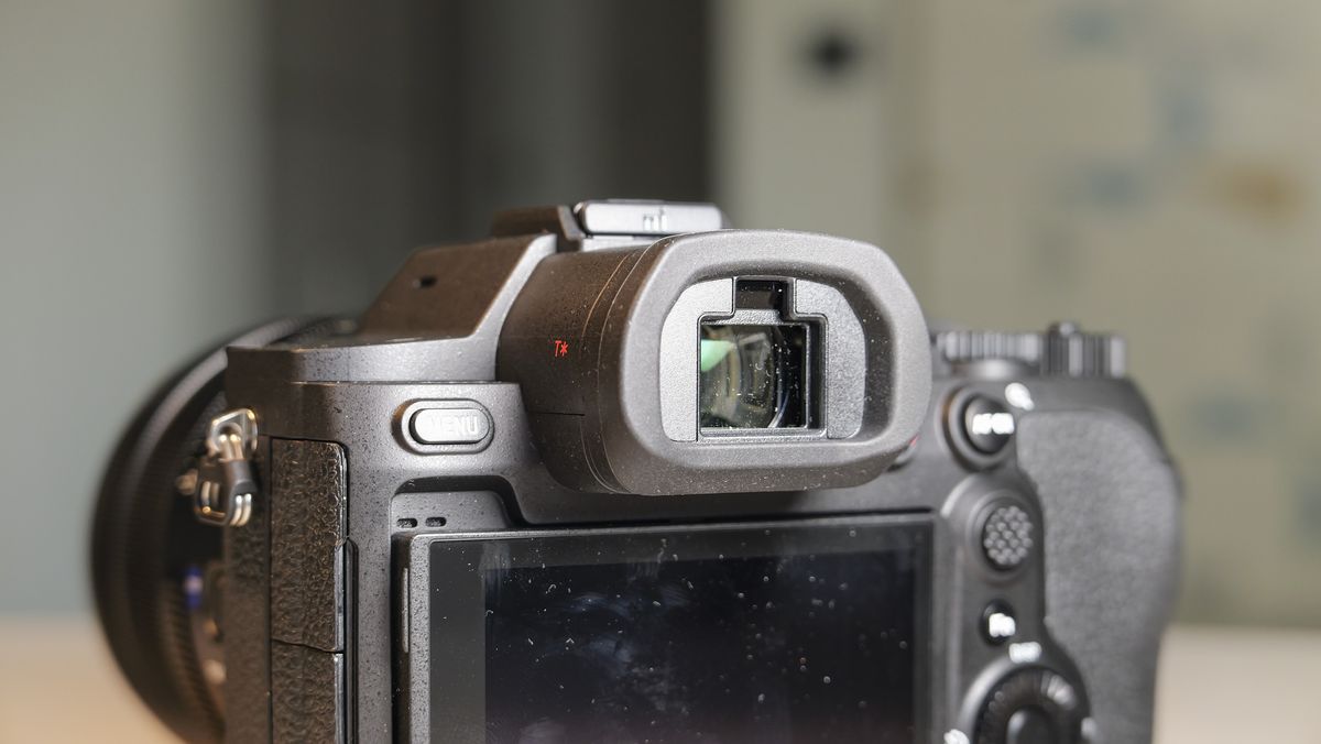 The Sony RX10 V bridge camera on a white table with a patterned wallpaper background, closeup of its viewfinder