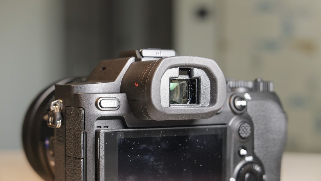 The Sony RX10 V bridge camera on a white table with a patterned wallpaper background, closeup of its viewfinder