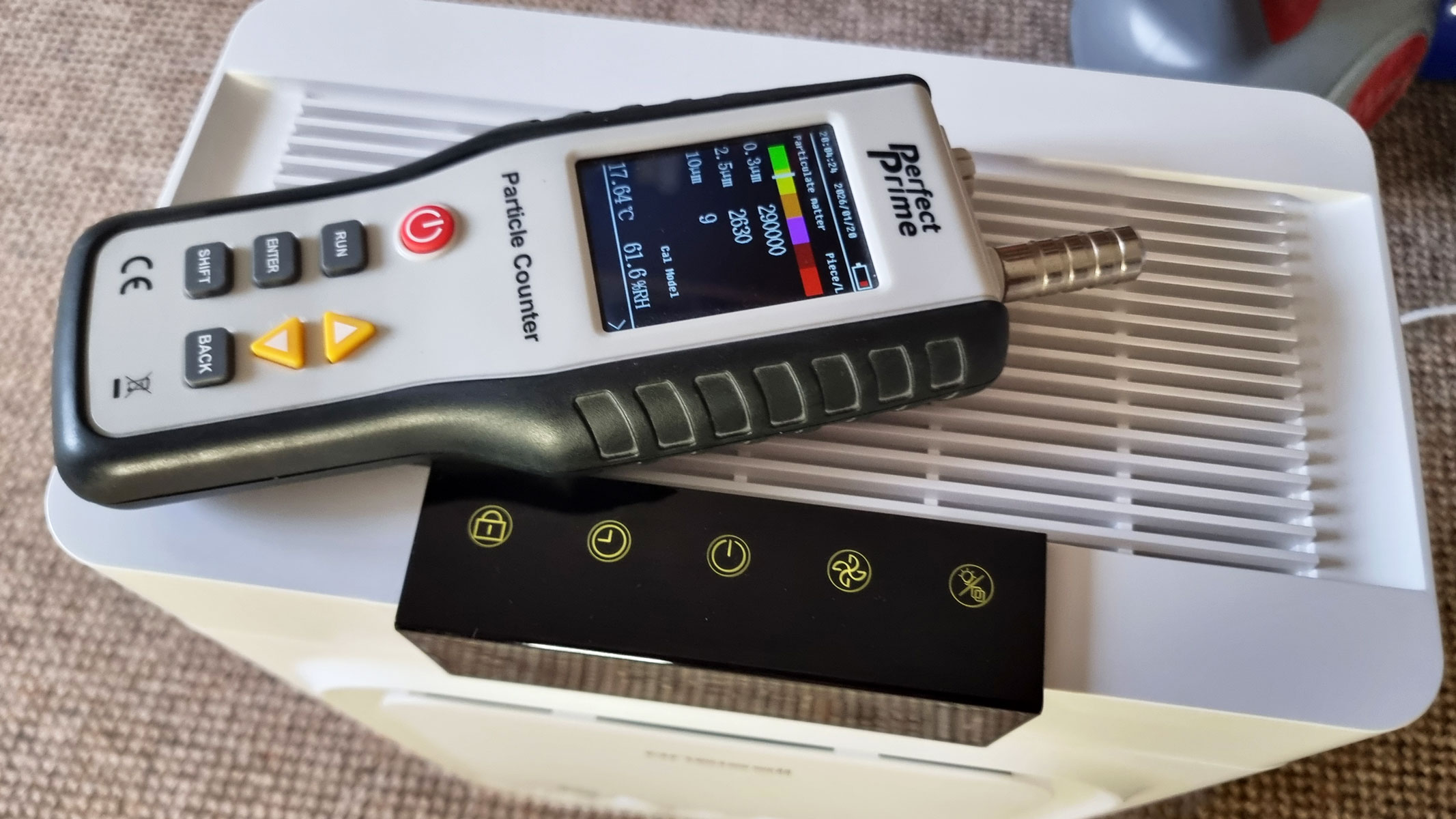 A picture of the Perfect Prime air particle counter laid flat on top of the Oneisall Pet Air Purifier