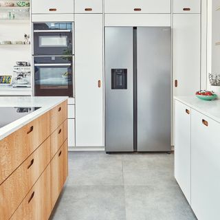 A modern kitchen with stainless steel fridge, built-in oven and microwave appliances and sleek finger pull handled cabinetry