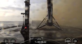 A black and white spacex falcon 9 rocket first stage sits on the deck of a ship at sea.