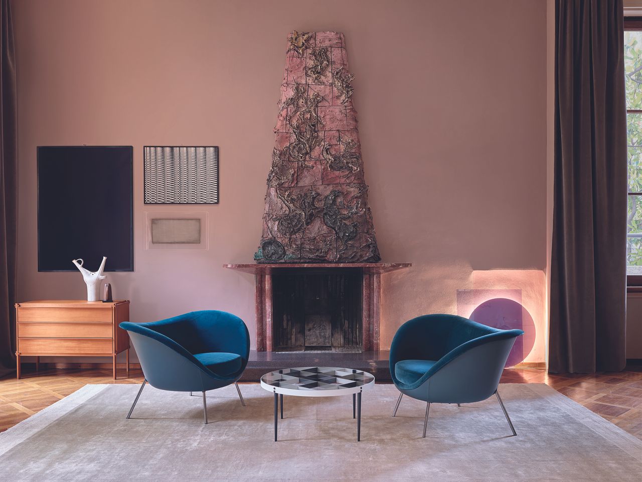 Gio Ponti chairs upholstered in blue velvet and coffee table in front of pink wall with fireplace