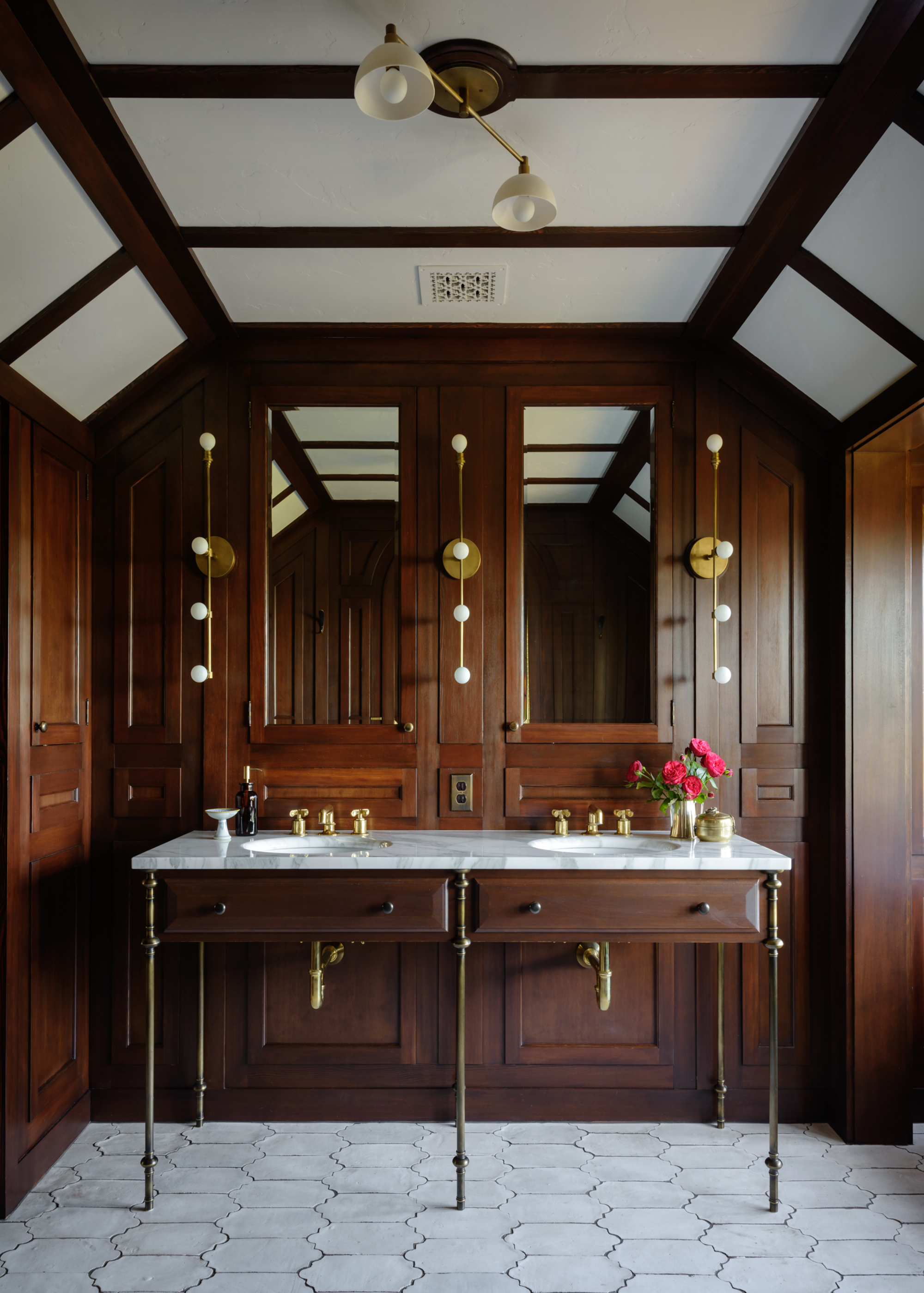 A bathroom with wooden walls, a tiled floor, and a double marble vanity
