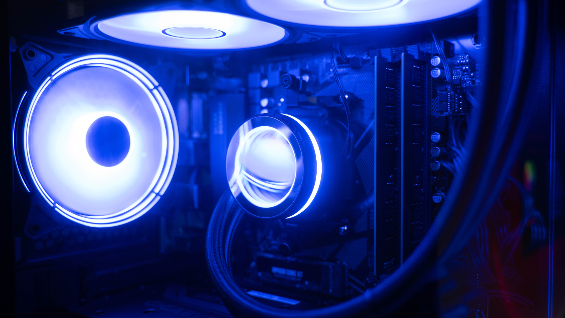 Closeup Image Of Gaming PC With Blue RGB Lighting - stock photo. Close up image of watercooled gaming pc motherboard and blue rgb lighting with a focus on the cpu cooler and wiring ready to play the latest games.
