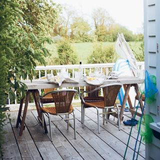 decked veranda of a beach cabin with table, chairs and fishing equipment