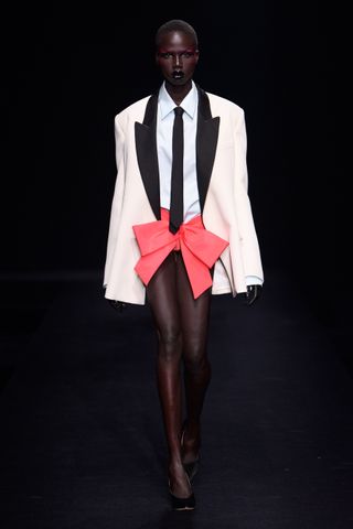 Woman on Valentino runway in tuxedo with bow