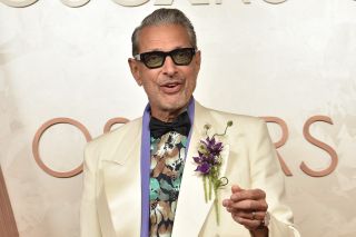 Jeff Goldblum smiling and holding his right hand up on the Oscars red carpet at the Dolby Theatre on March 2, 2025.