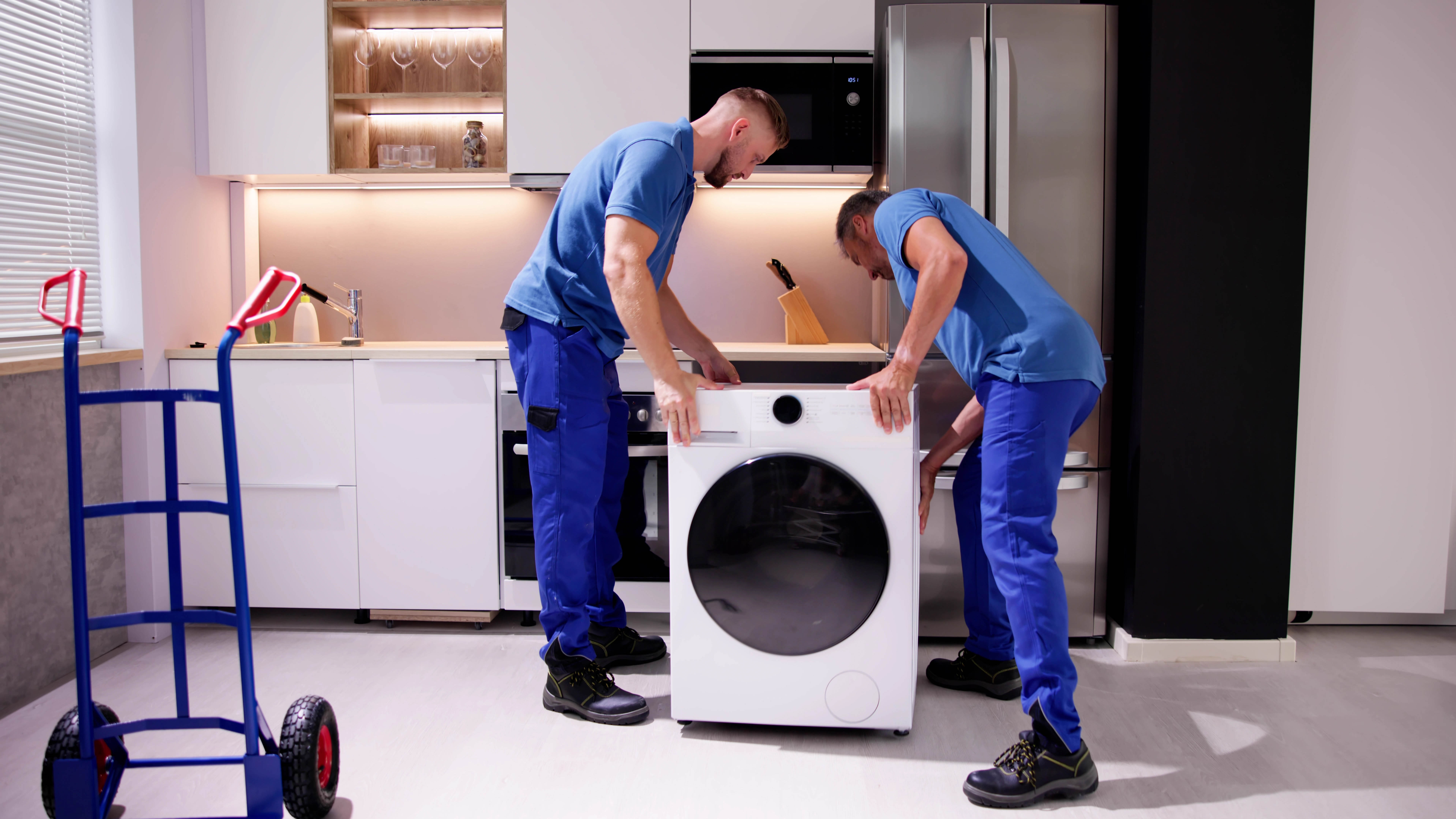 Двое мужчин устанавливают стиральную машину