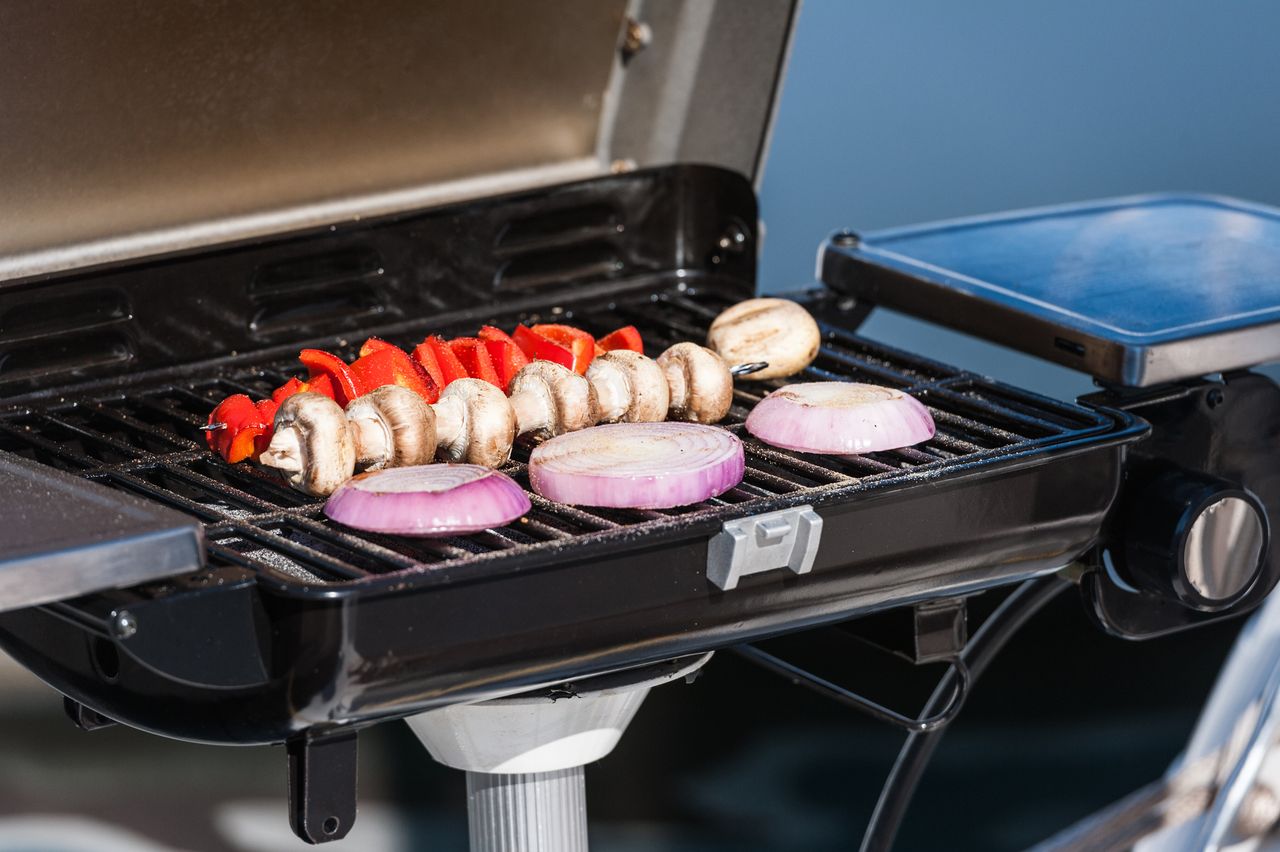 Onions, mushrooms, and peppers toasting on an electric grill