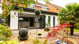 Anglian Cosy Room conservatory extension on detached brick house finished with cream render, black bi-fold patio doors on two sides