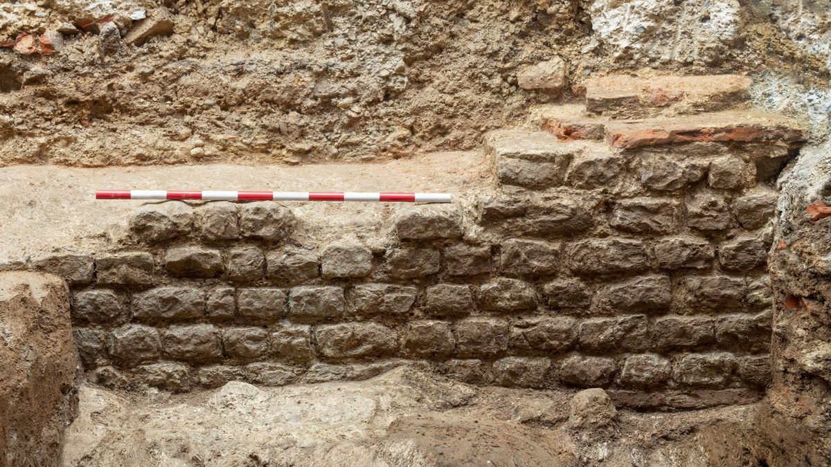 Six courses of ancient brick are stacked up in dirt.