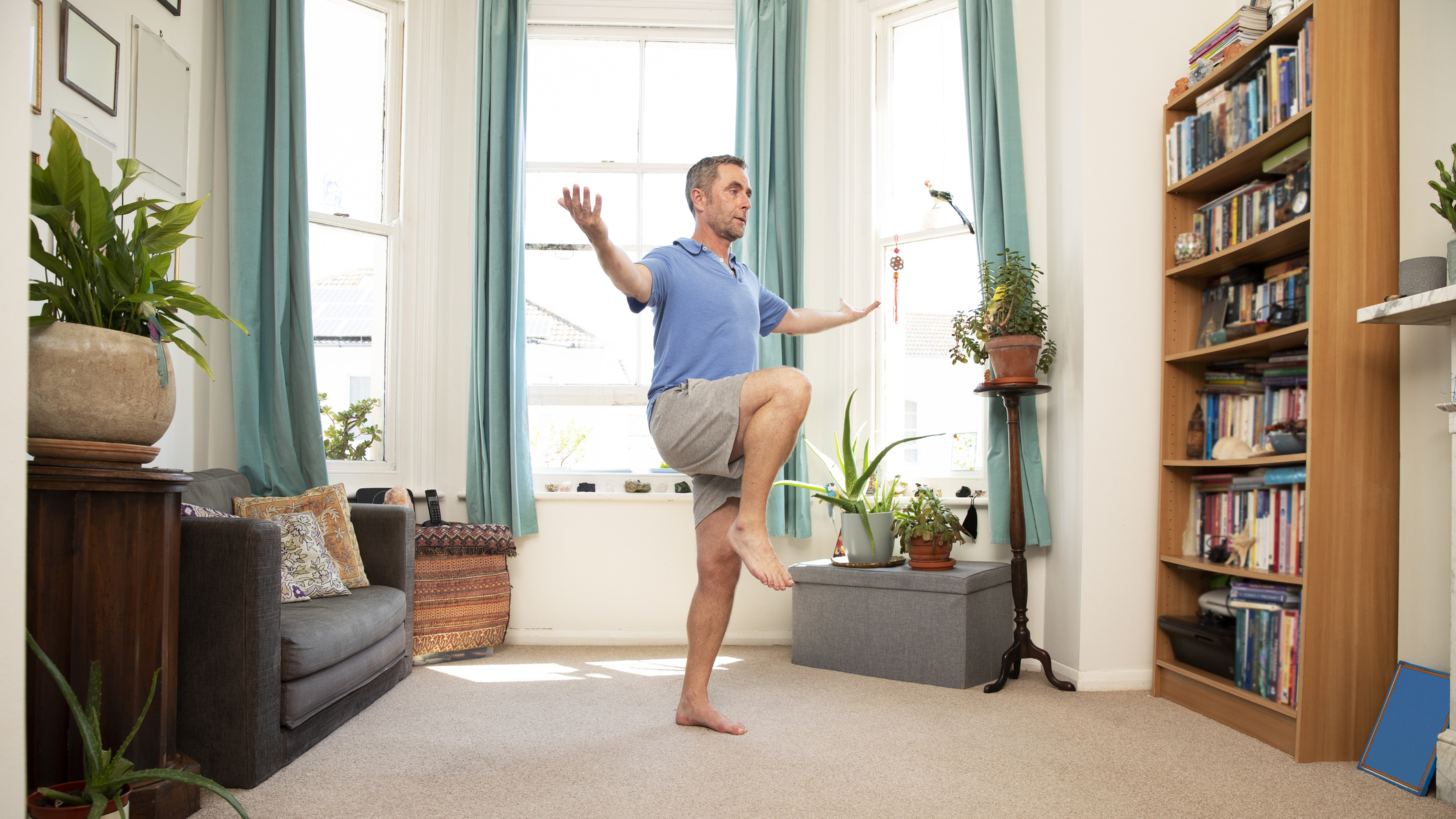 Man balances on one leg in living room
