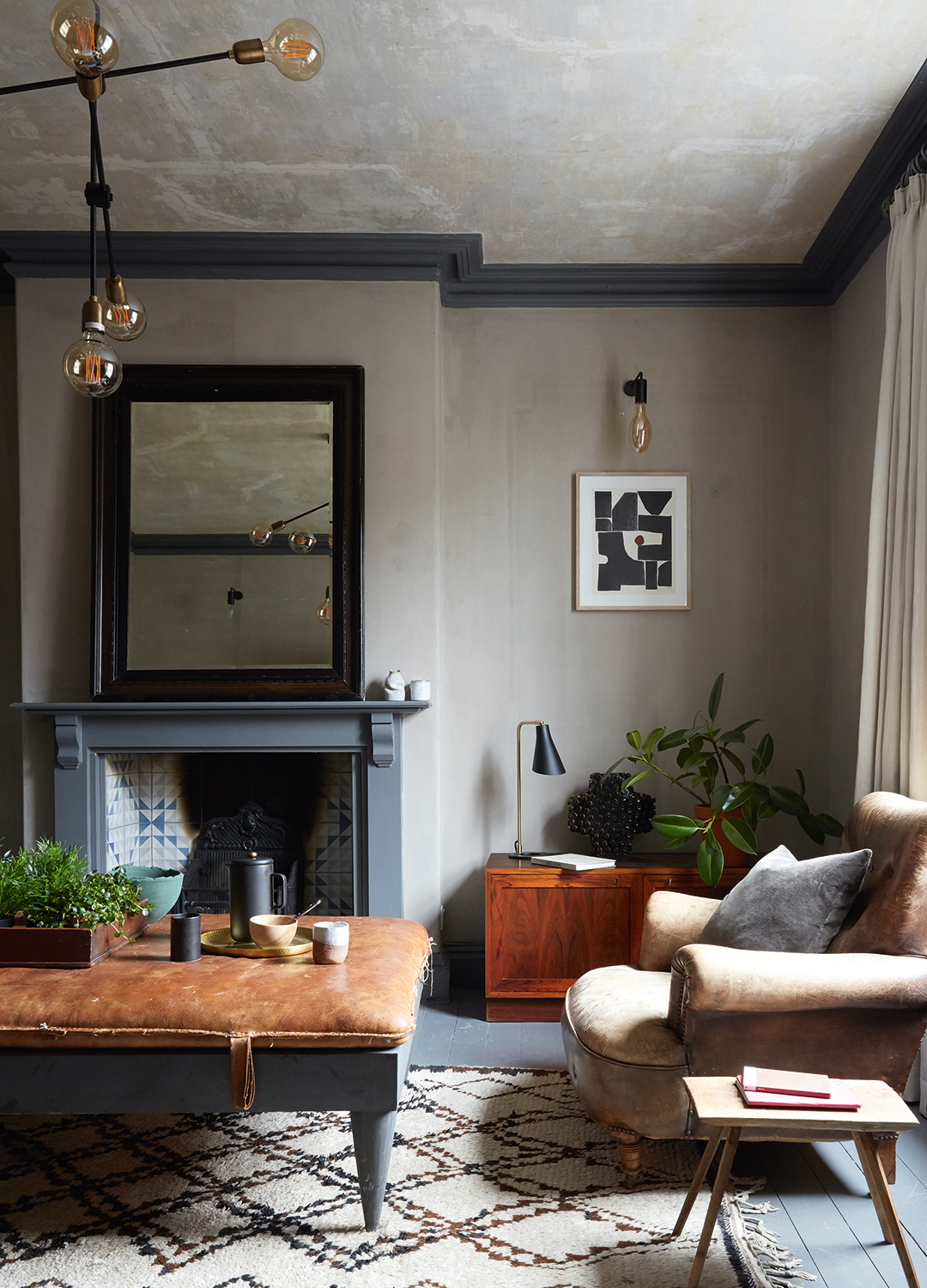 Living room with painted floorboards, fireplace and mirror and sofa in a former Victorian mill, a renovated period house