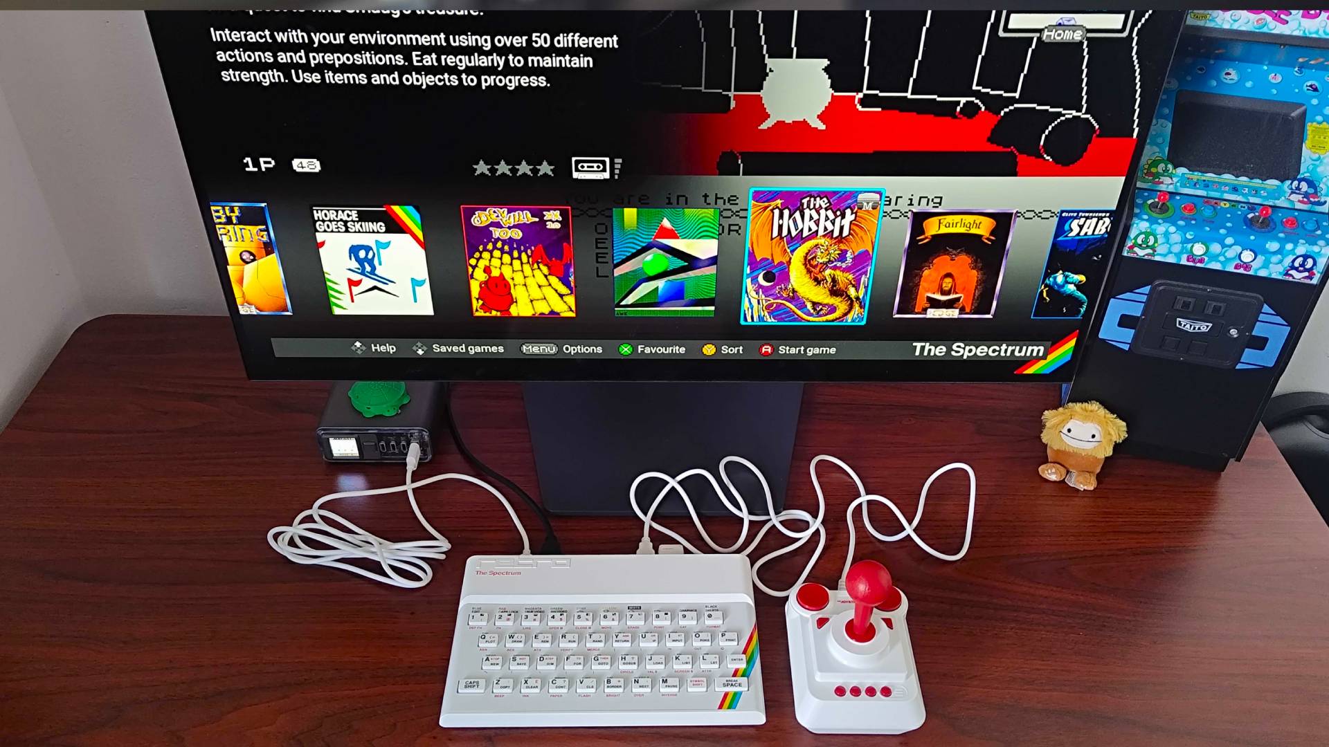 The Spectrum on woodgrain desk connected to LG OLED monitor with The Hobbit highlighted in menu.
