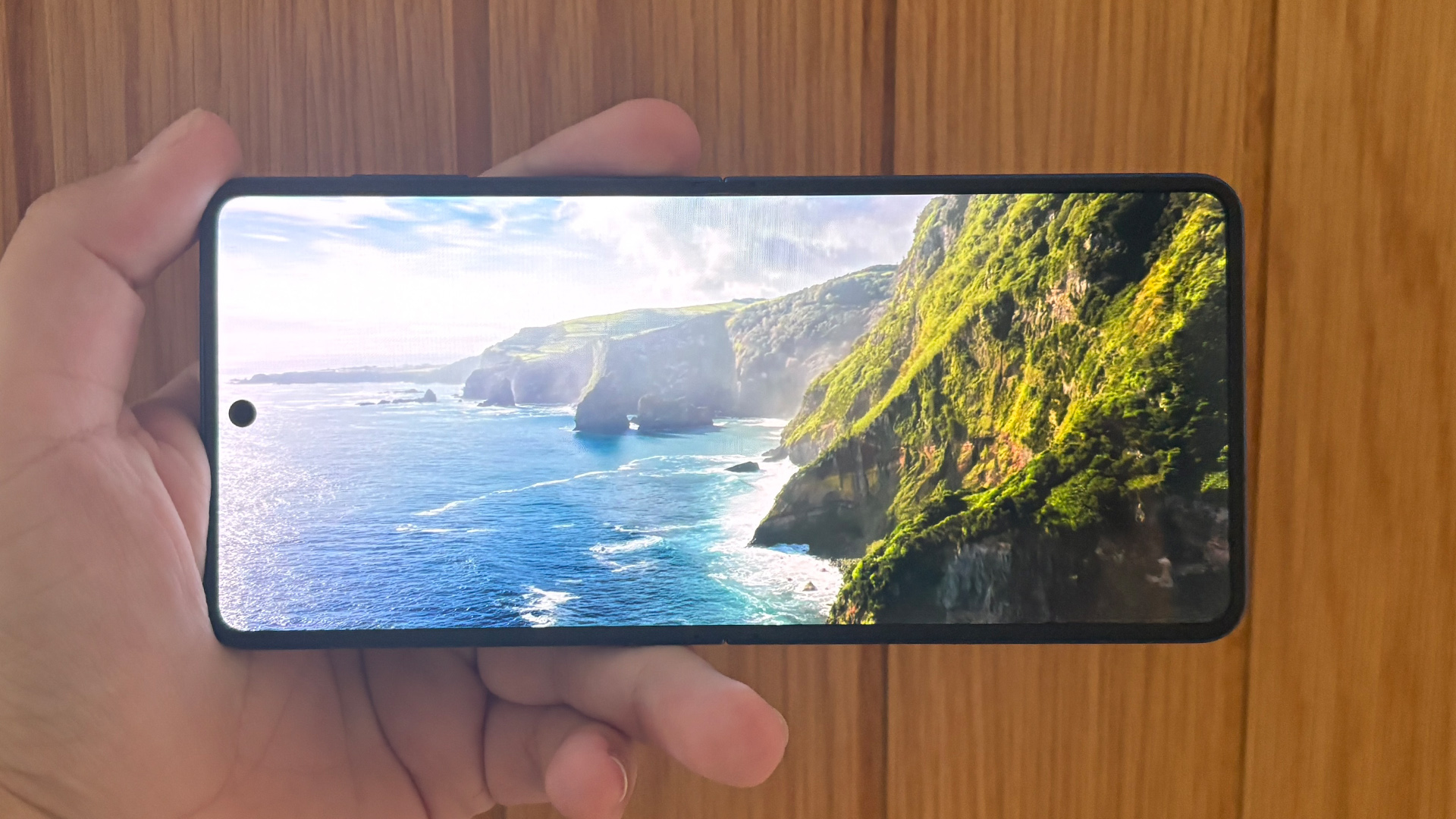Samsung Galaxy Z Flip 7 smartphone open in landscape view in hand showing coastal image