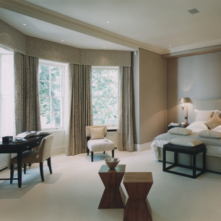 A smart bedroom with a bay window and curtains hung around it alongside down lighters