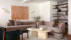 living room with curved velvet sofa, travertine coffee table, and floating shelves