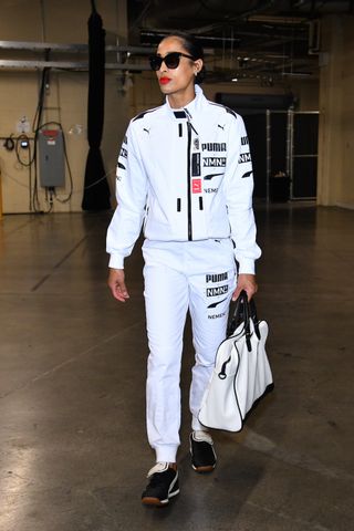 Skylar Diggins-Smith #4 of the Seattle Storm does a tunnel walk at the 2024 WNBA finals wearing a white pump sweatsuit and red lipstick