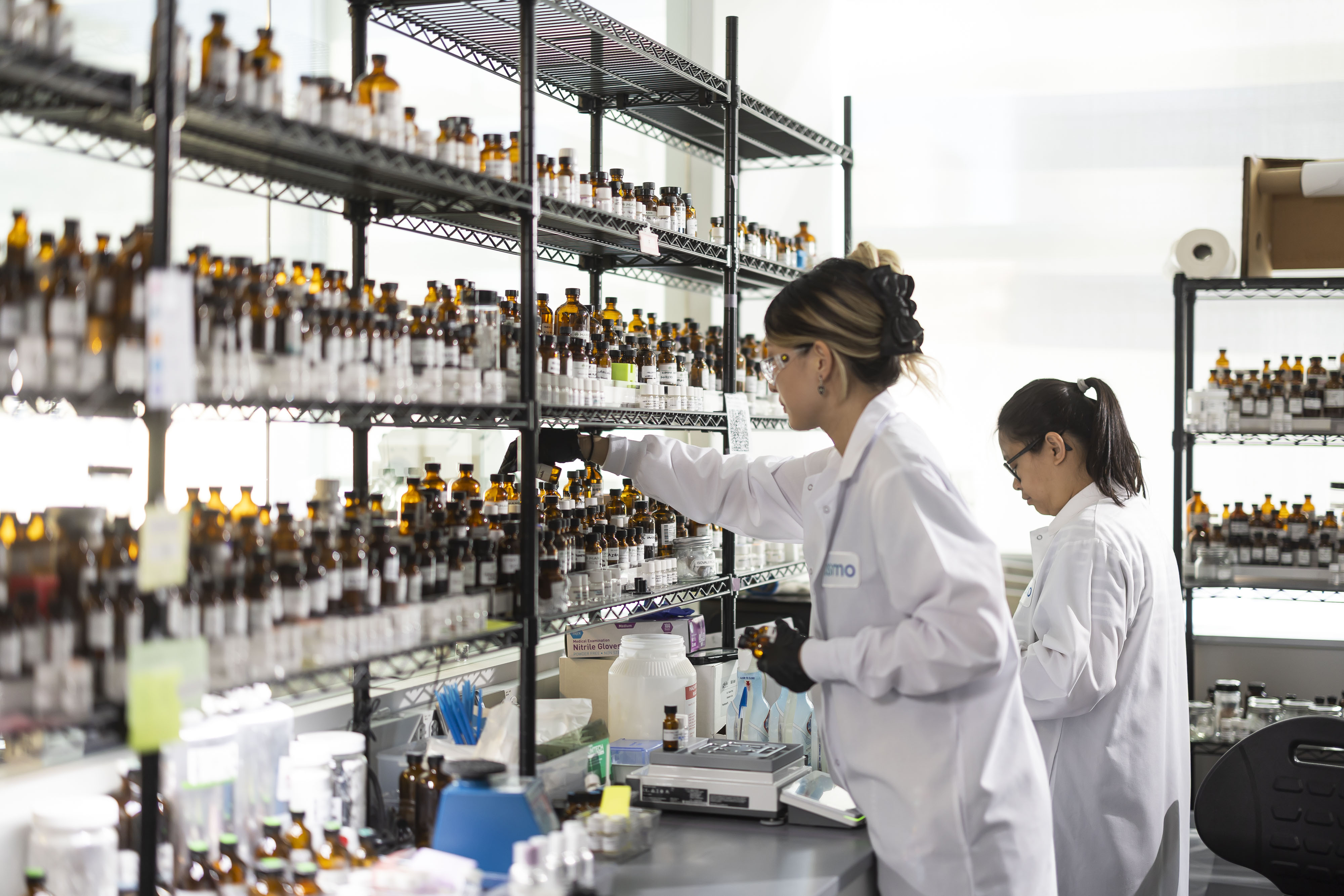 Perfumers in lab coats in a lab full of vials
