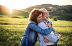 Side view of senior couple hugging outside.