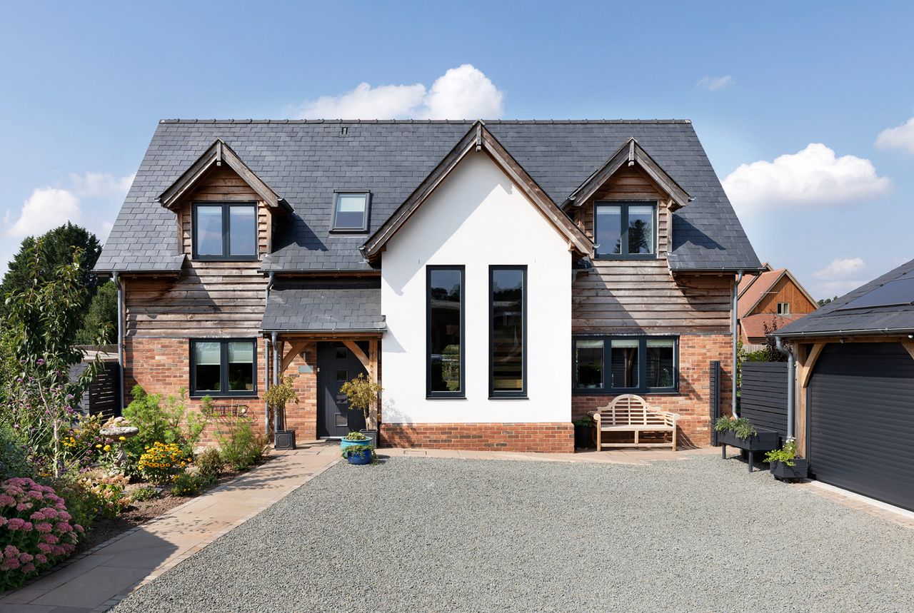 A custom build oak framed home with white render, timber cladding and a driveway