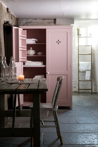 kitchen with worn grey stone floor rustic table and pink pantry