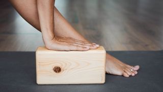 A wooden yoga block being used during a stretch