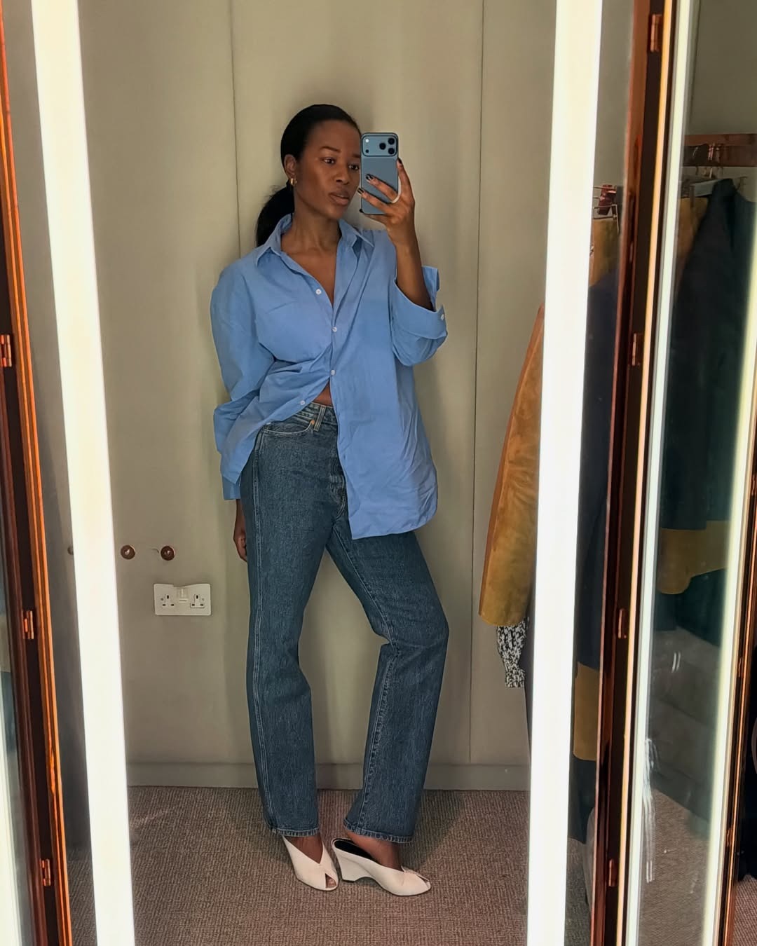 Woman in blue shirt, jeans, and white shoes