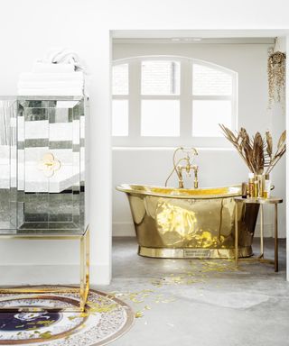 An example of ensuite ideas showing a gold bath tub in front of a window