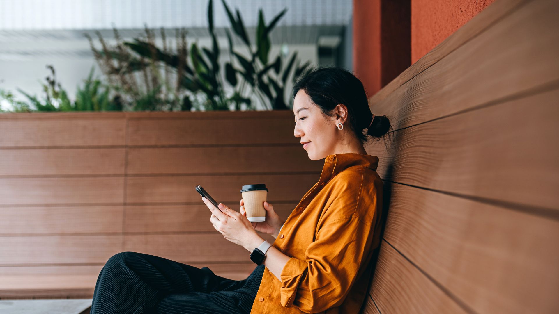 Woman looking at phone sitting down on bench