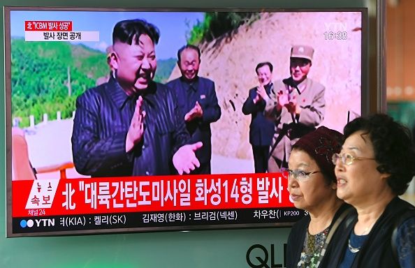 Women walk by news coverage of the North Korean missile launch.