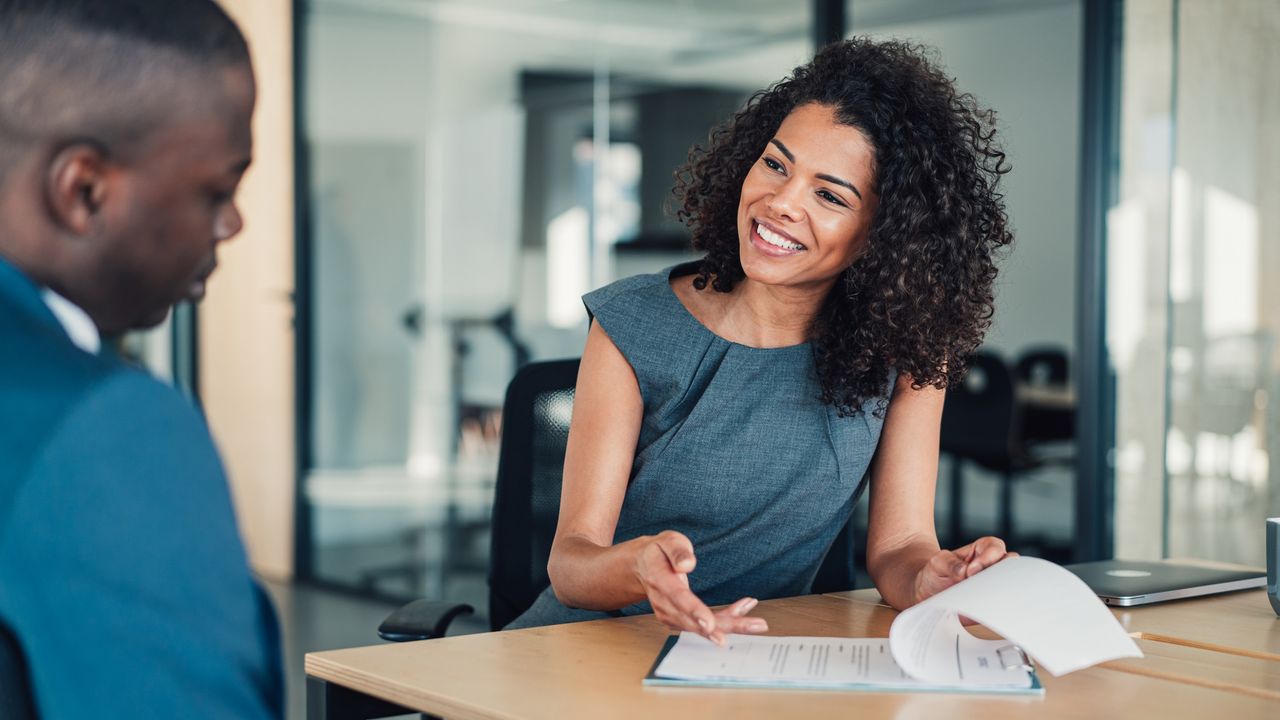 A sales executive goes over a sales proposal with a businessman in a conference room.