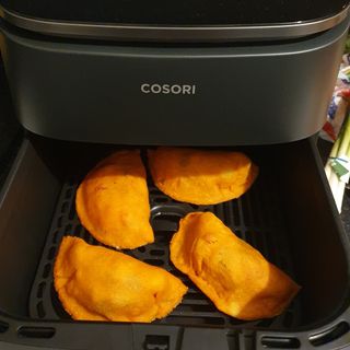 Empanadas in an open drawer of the COSORI Turbo Blaze air fryer