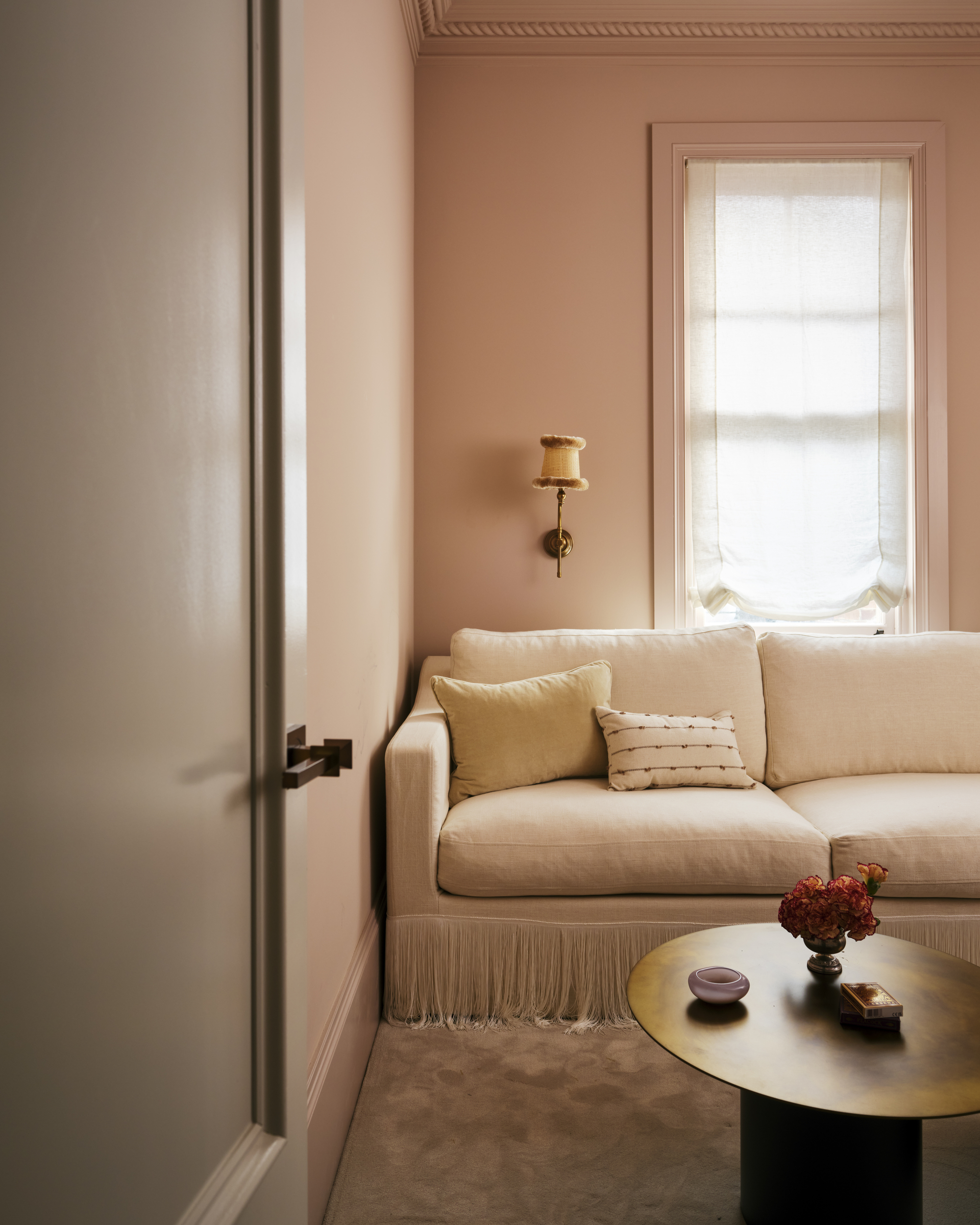 a peach living room with a fringed sofa