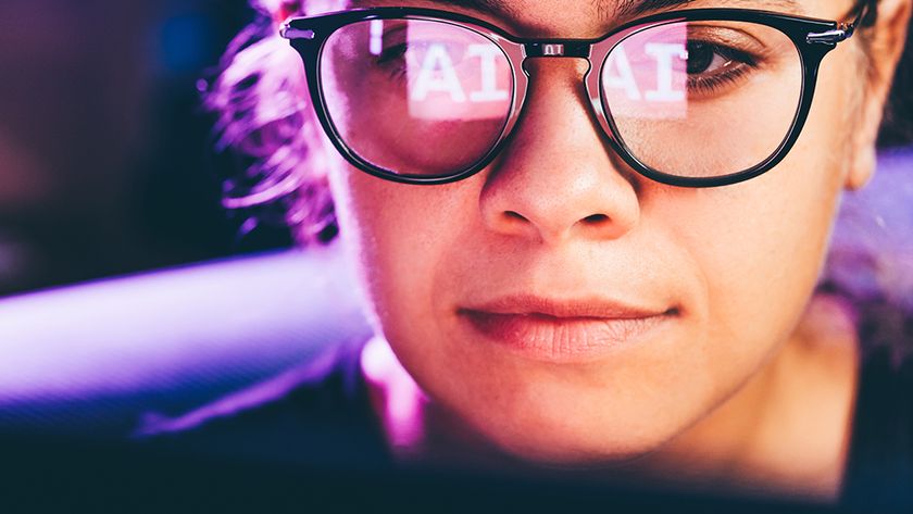 A designer working at a computer with AI written in the reflection on her glasses