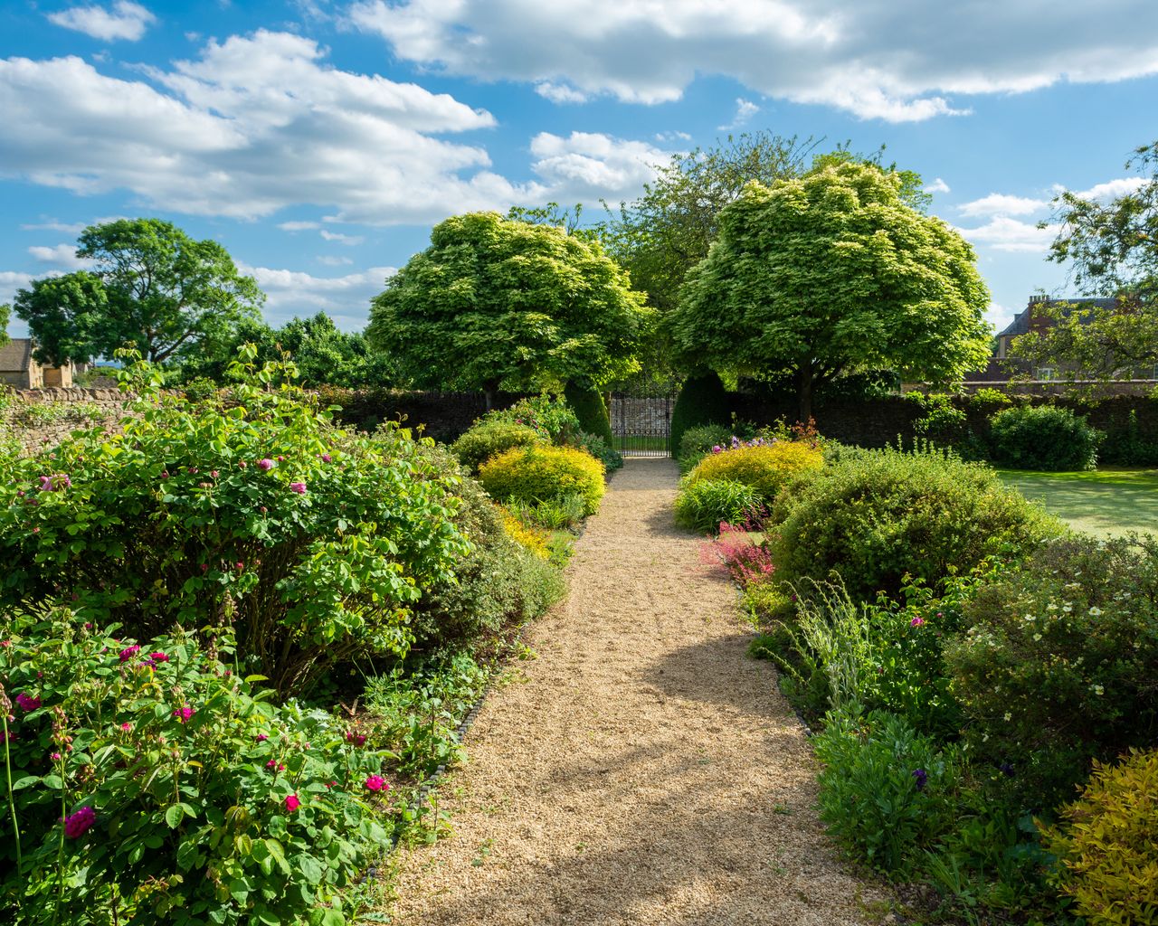 flower beds either side of long gravel garden path