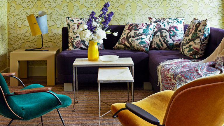 colorful living room with yellow patterned wallpaper, purple sofa and yellow chair