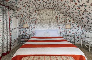 patterned bedroom with floral wallpaper and striped red bed cover