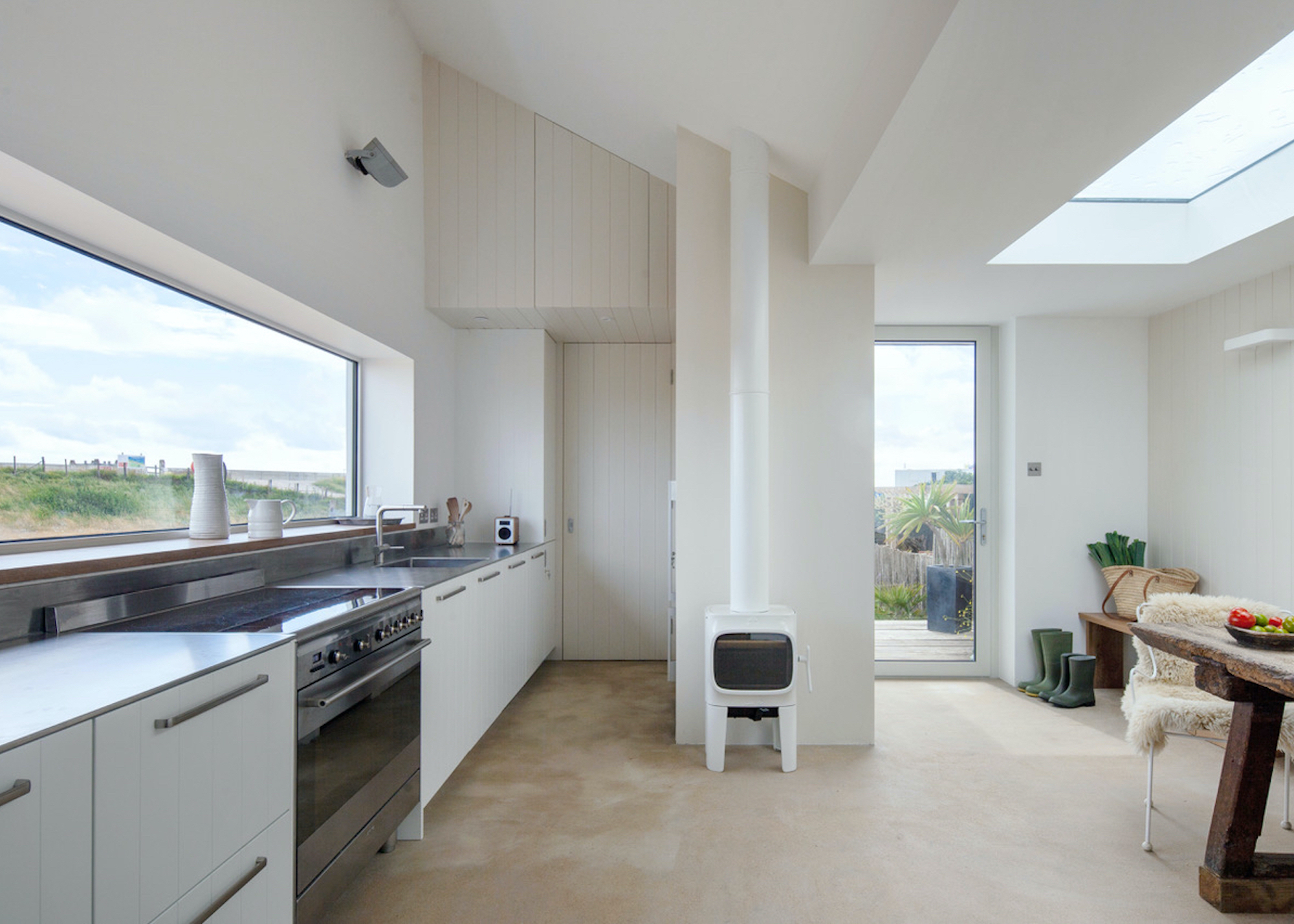 A kitchen extension with white washed walls, white cabinets and a stove.